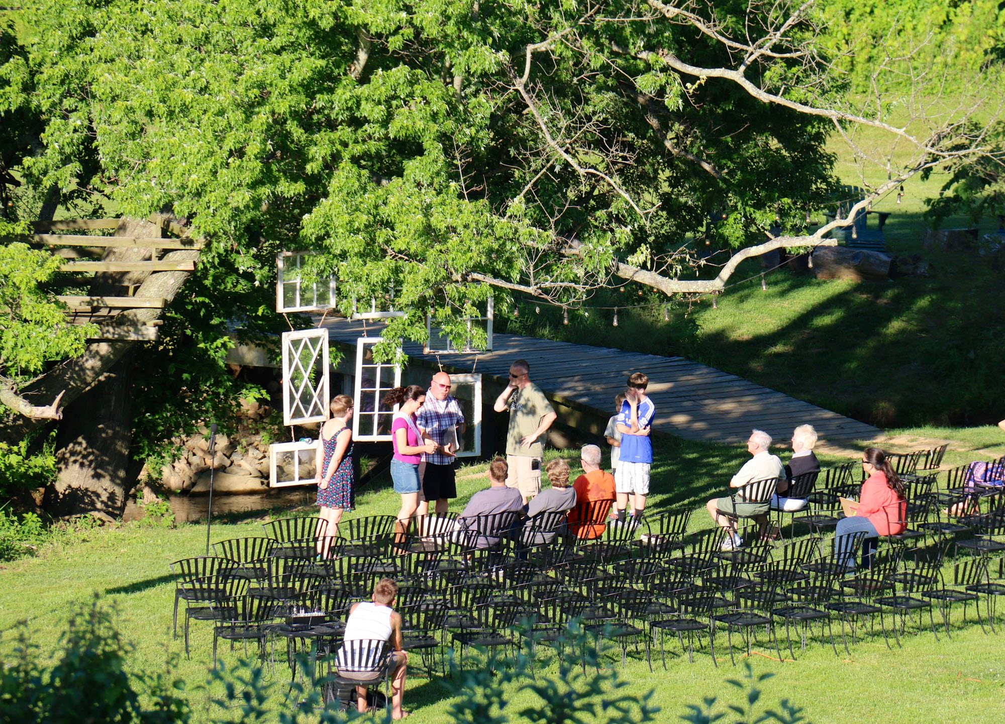 Guests arrange seats on a lush lawn in preparation for a scenic outdoor wedding ceremony.