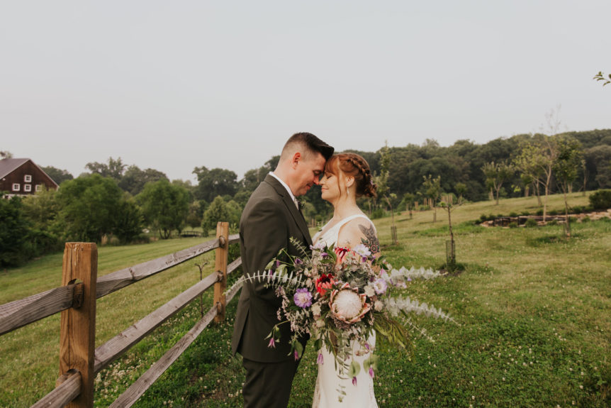 Wedding couple sharing a quiet moment outdoors with a beautiful bouquet