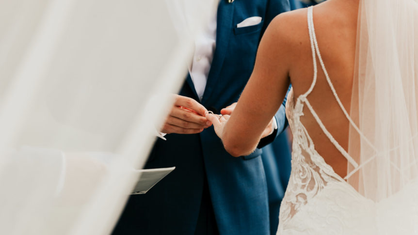 Close-up of a bride and groom exchanging rings during their intimate elopement ceremony.