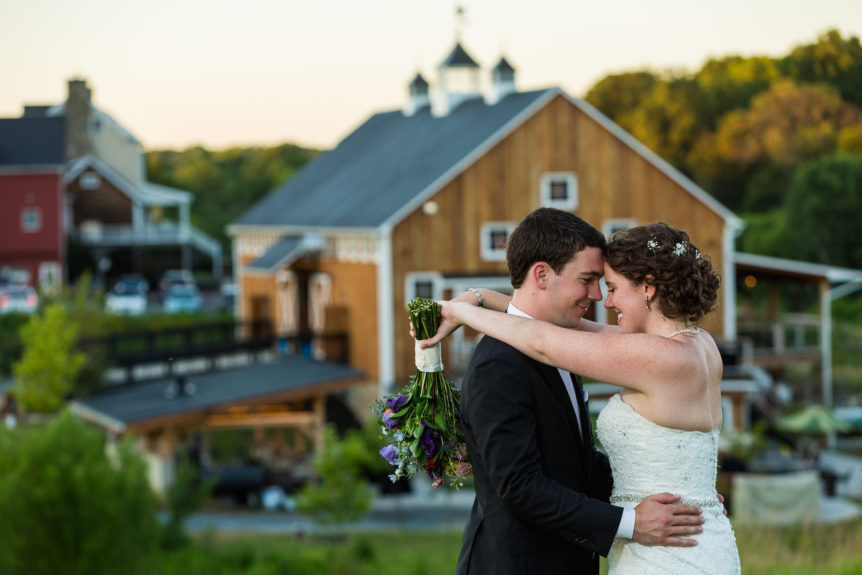 Couple Embracing with Rustic Barn Wedding Venue in the Background
