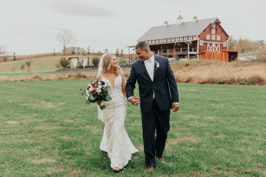 Happy Bride and Groom Holding Hands and Gazing at Each Other at Barn Wedding