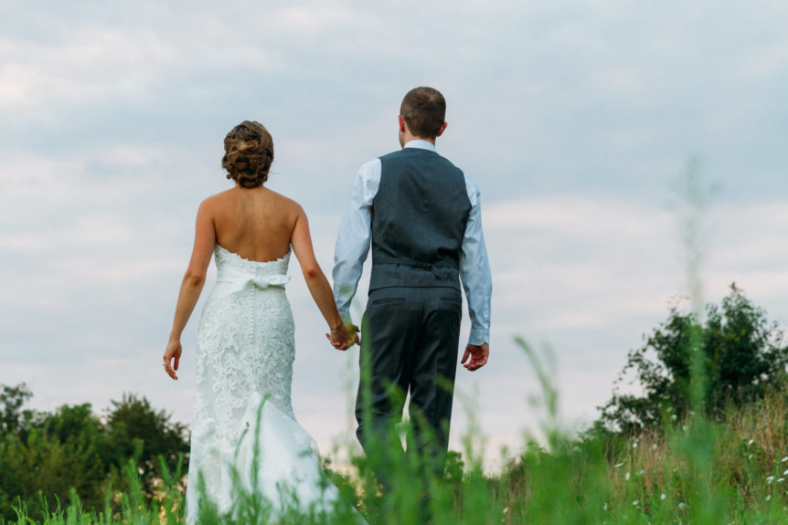 Bridal Couple Walking Hand in Hand in a Picturesque Field