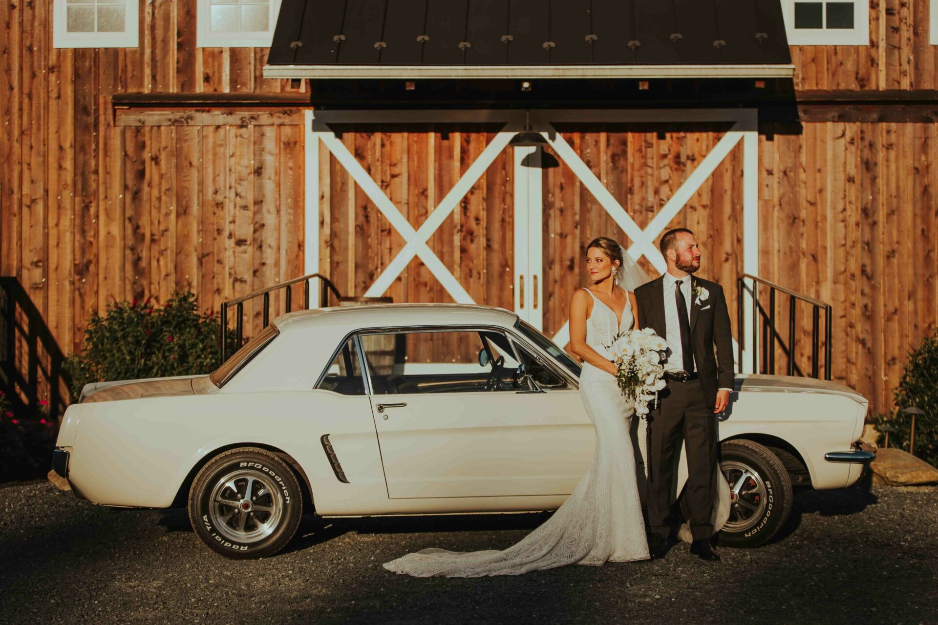 Bride and Groom with a vintage car in front of a rustic barn