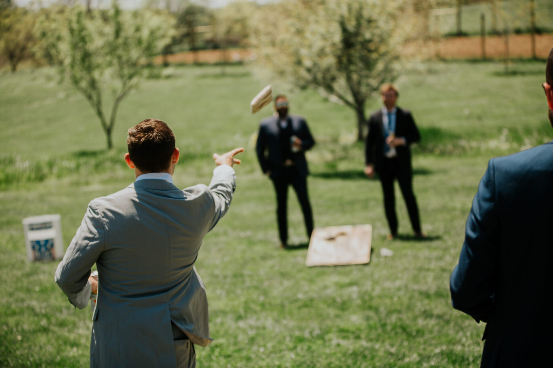 Zion Springs Real Wedding groom and groomsmen playing cornhole on the estate lawns
