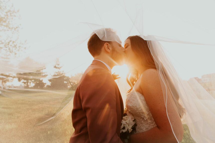 Zion Springs bride and groom kissing with sunlight and airy veil caressing them
