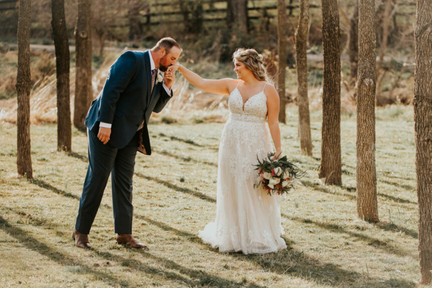 Zion Springs bride and groom in walnut grove with groom gallantly kissing bride's hand