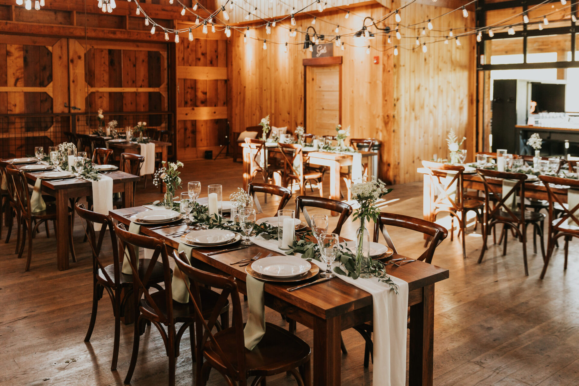reception banquet with tables and chairs and place settings for elegant wedding in rustic barn