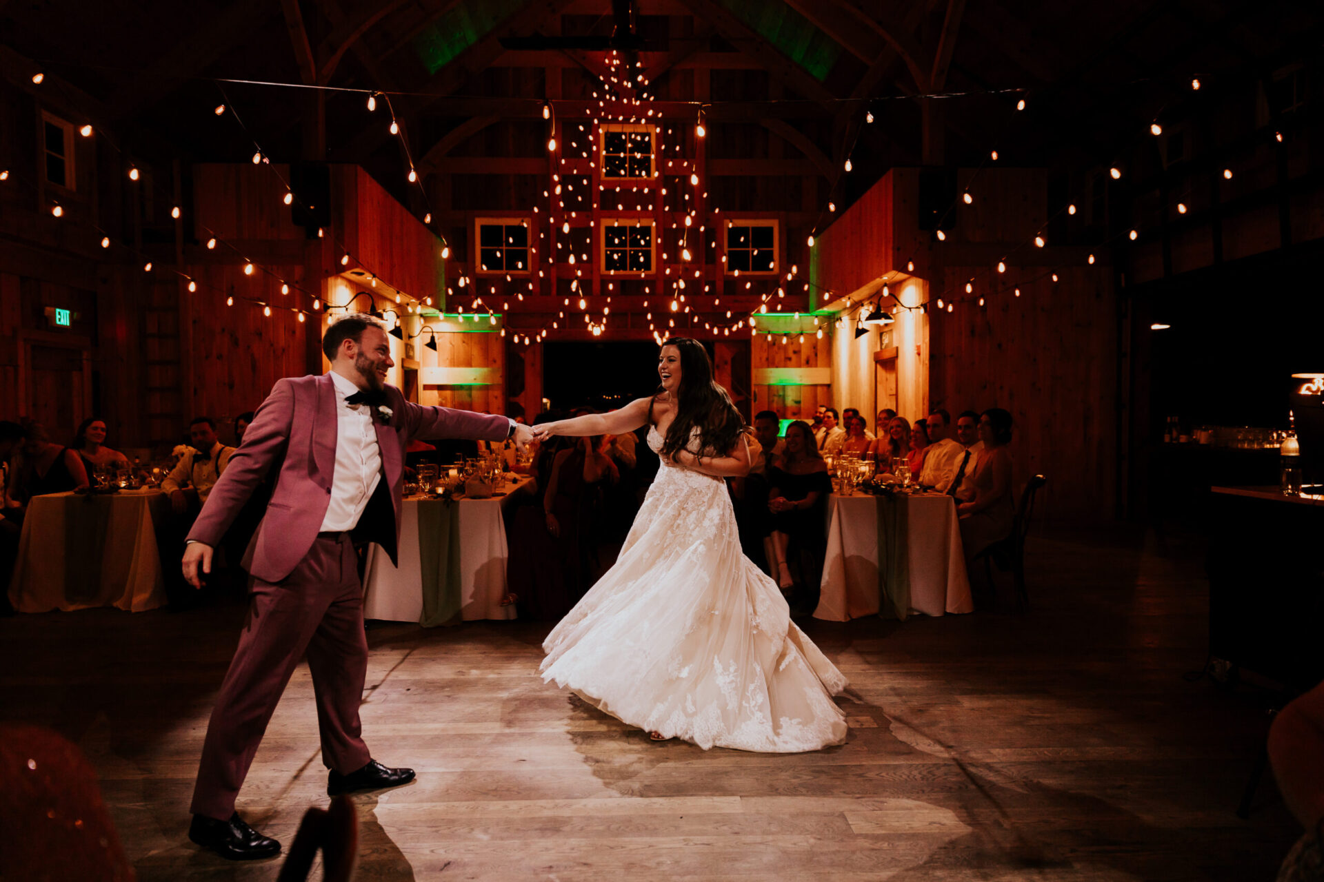 Zion Springs bride and groom dance in rustic barn with twinkling lights