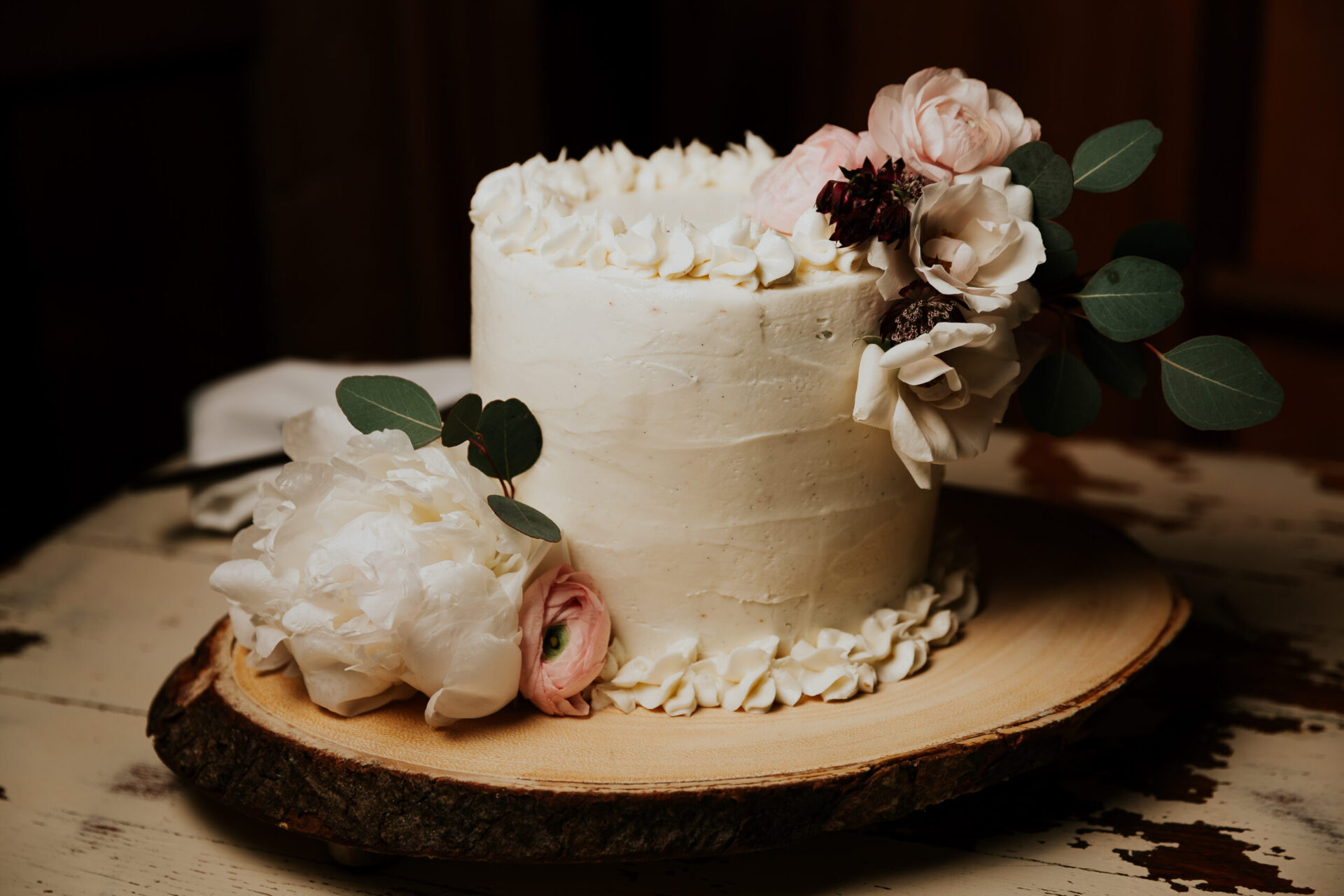 Zion Springs wedding cake with white and pink flowers on wood platter