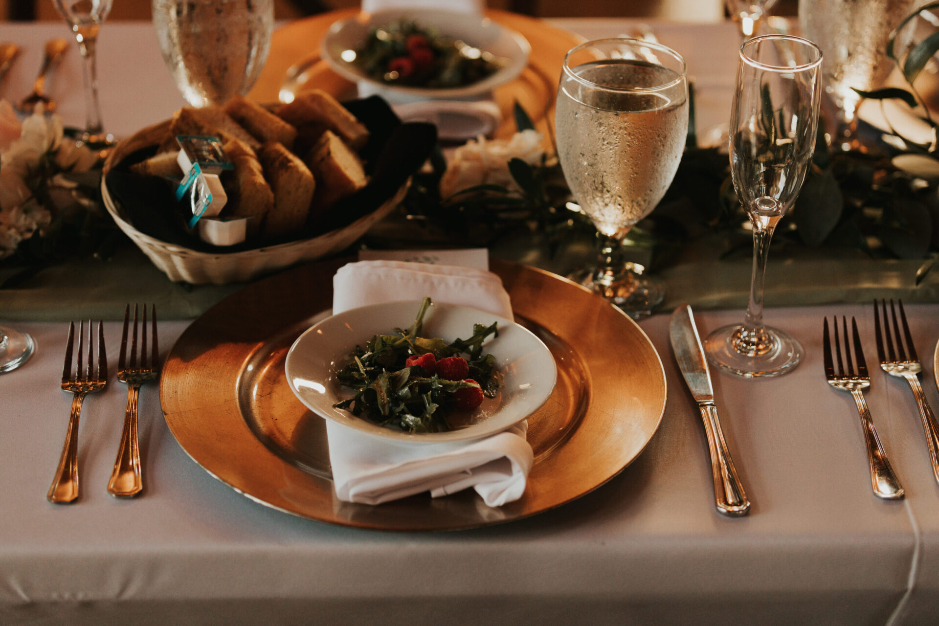 Zion Springs reception dinner with gold platter and table setting, cold ice water, champagne flute, bread basket