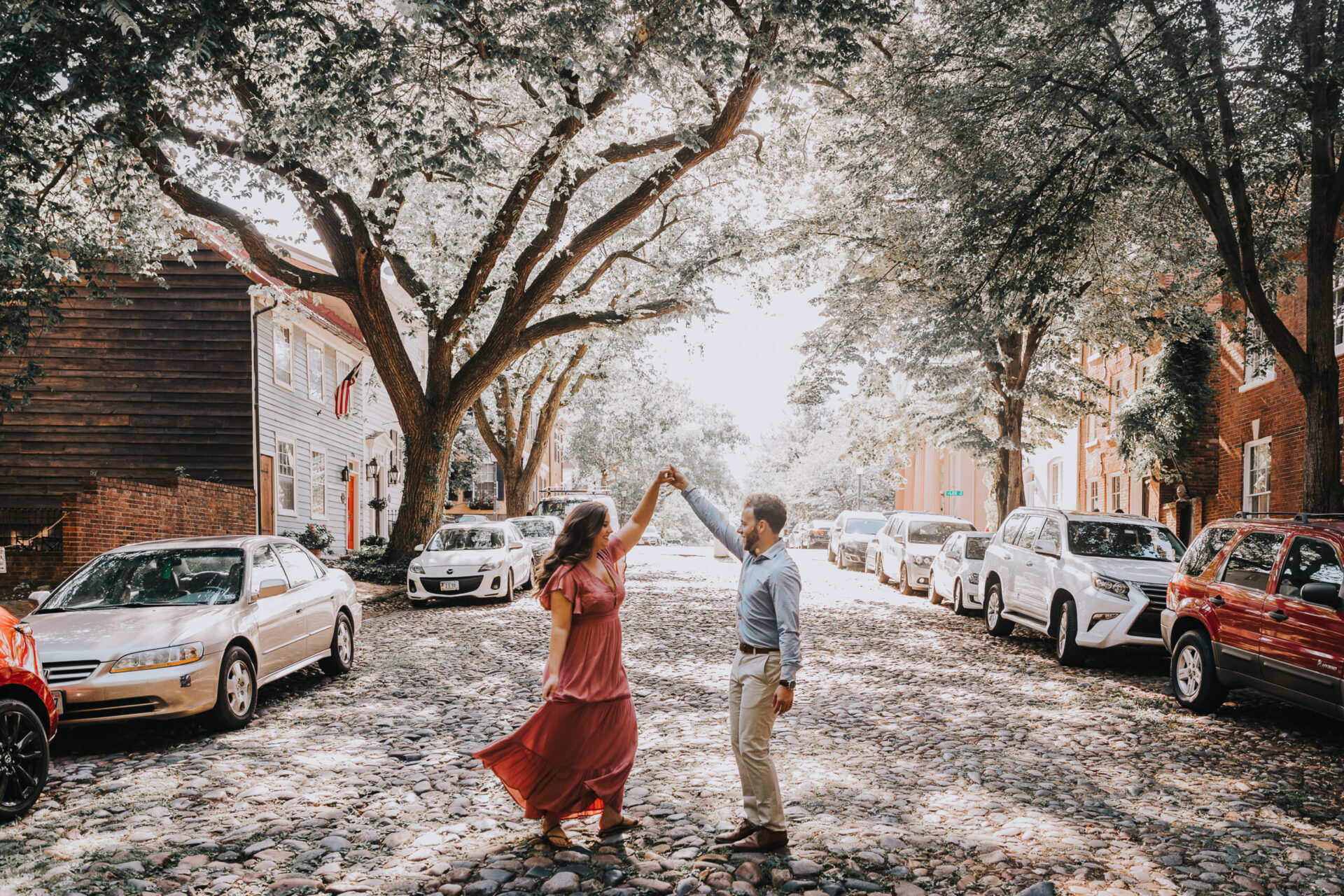 Zion Springs engagement shot couple on cobbled street dancing in sunlight