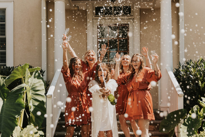 Zion Springs Real Wedding bride and bridesmaids celebrating with champagne on steps of Manor House