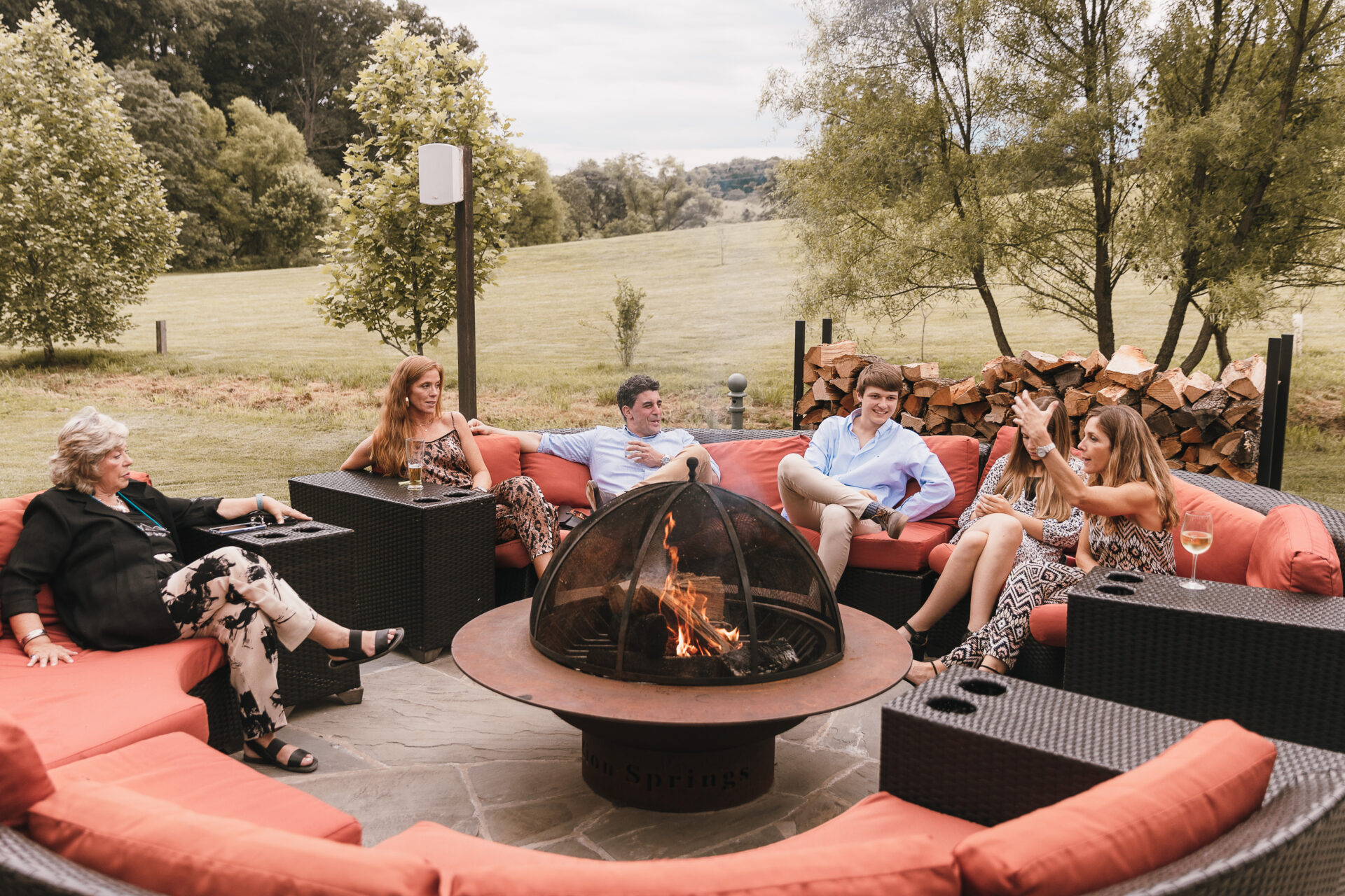 people seated around fire pit at rustic barn venue