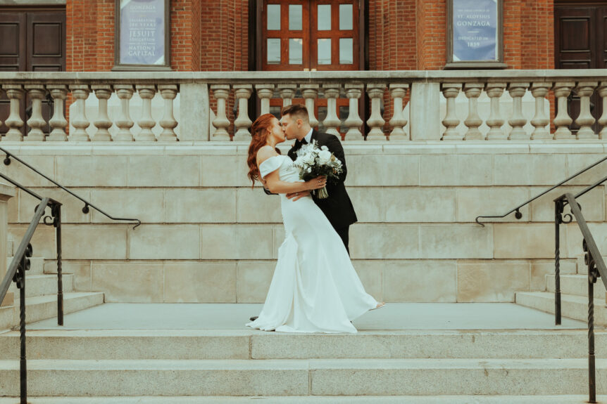 bride and groom kissing on steps of official building
