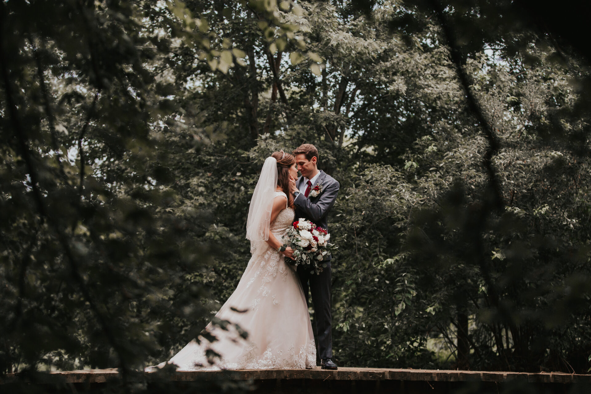 Bride and groom on a wood bridge surrounded by trees in summer