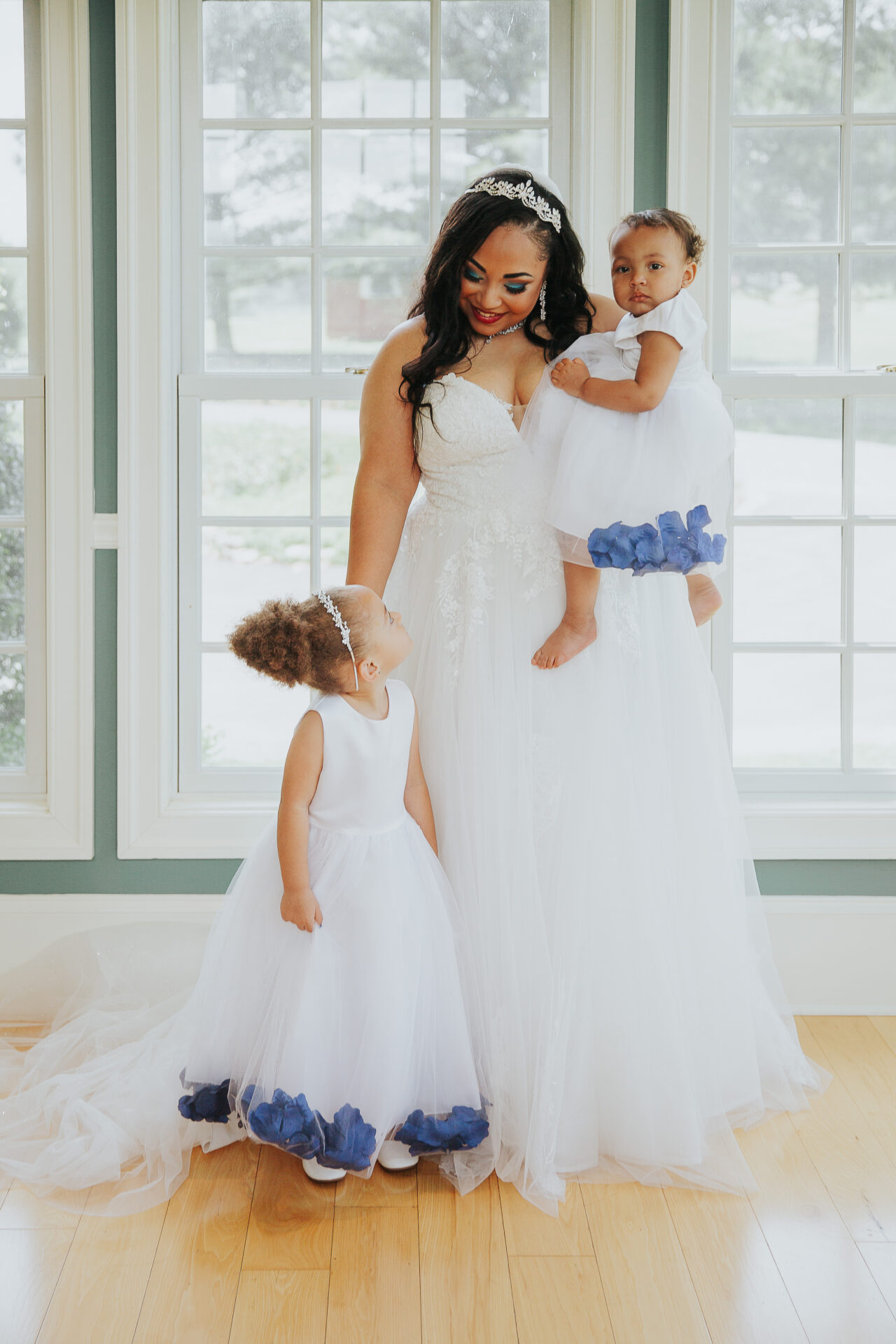 bride with flower girl and baby in sunlit room