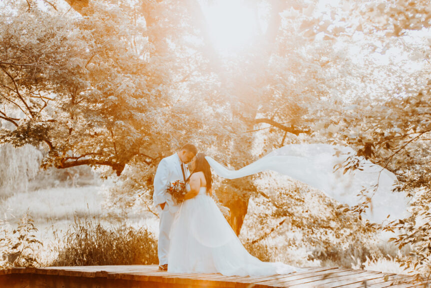 bride and groom on bridge with summer sun highlights