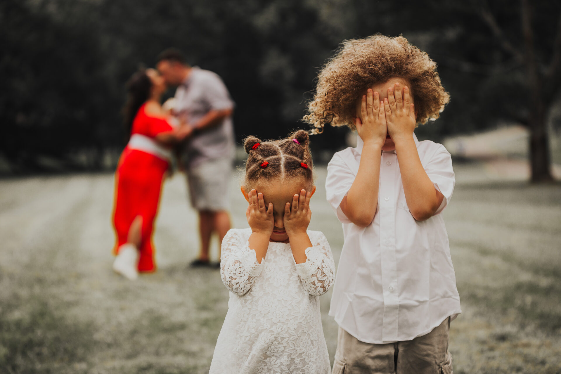 children hiding faces from parents kissing