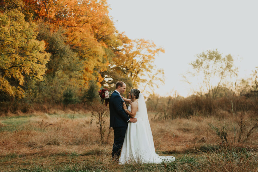 fall wedding with autumn leaves backdrop to bride and groom