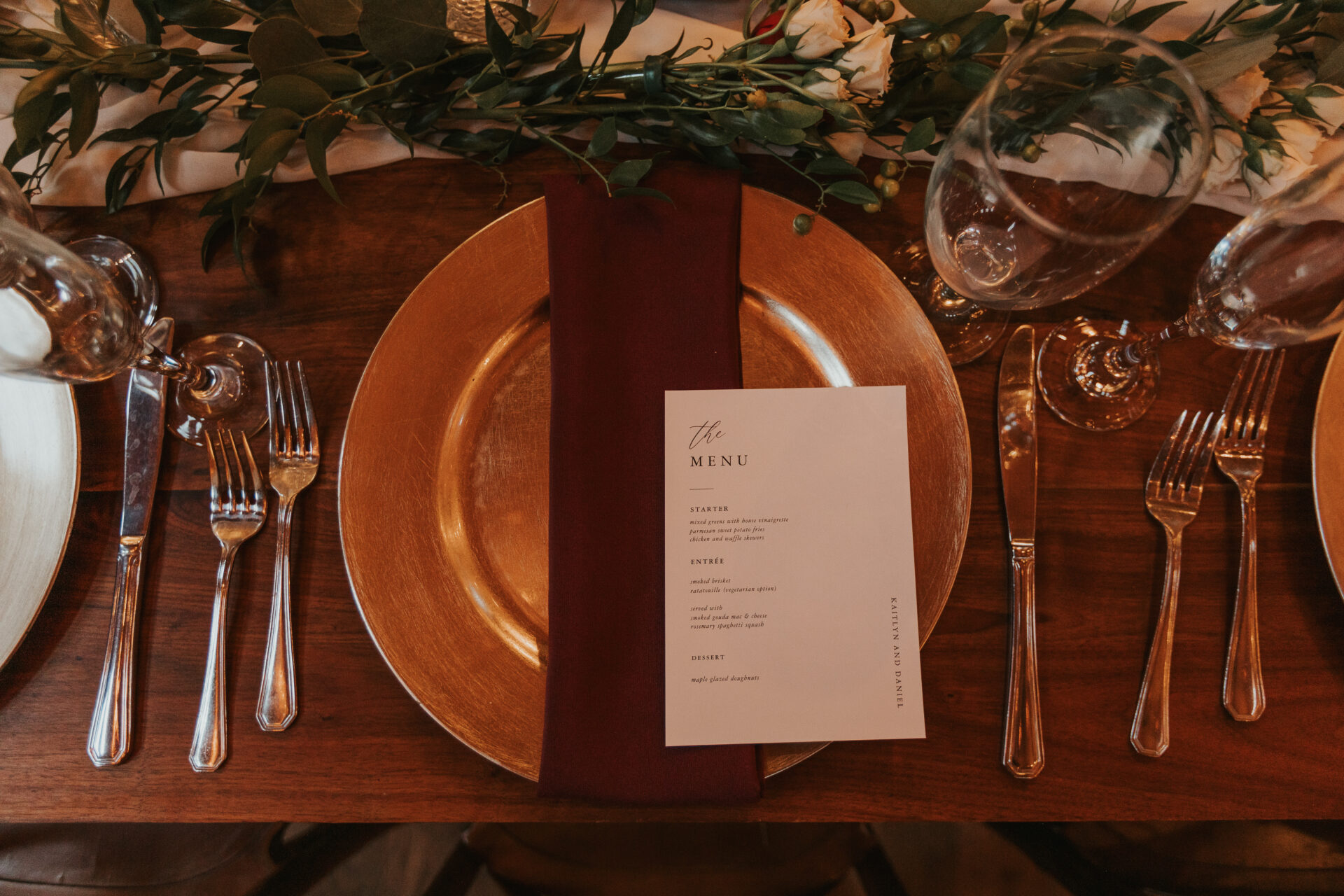 Place setting, table, glass, gold platter, gold server, menu, wedding reception