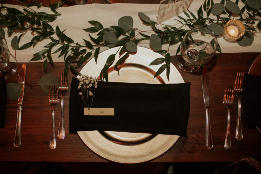 place setting, wedding dinner, black napkin, gold plate, rustic barn