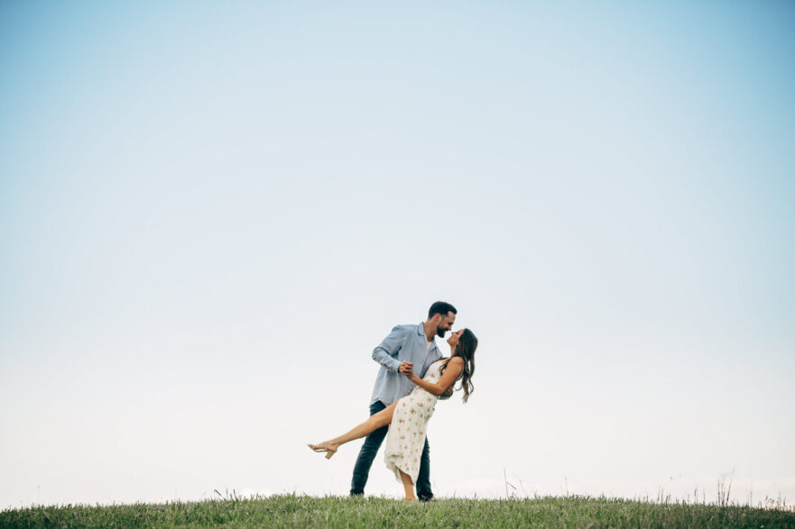 Engaged couple sharing a romantic dip kiss during a wedding venue tour.